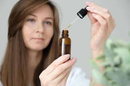 Woman holding CBD oil bottle and looking at the dropper