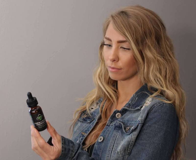 Woman looking at CBD oil bottle in her hand
